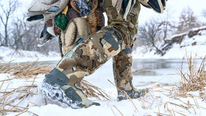 A duck hunter walking through the snow while wearing the KUIU HD Mud Boot in Valo Camouflage.