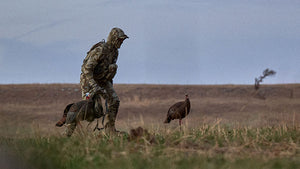 Turkey Hunter in Valo Camouflage setting turkey decoys in a field