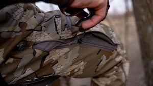 Male hunter in head to tote KUIU Valo camouflage highlighting Encounter LT Pants zippered mesh-lined hip vents.