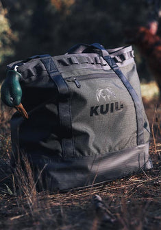 Close-up of KUIU CORDURA® Tote Bag in Stone Grey Color on grass with a duck decoy head visible