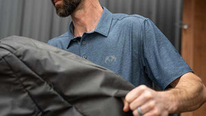 Male with a KUIU Performance Polo in Heather Navy loading truck with KUIU Ttavel gear.