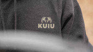 A man working outdoors in his khaki heather KUIU Base Camp Pullover.