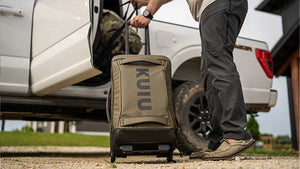 Male getting ready to hit the road with his KUIU's Waypoint Roller Bag and Base Camp Duffel.