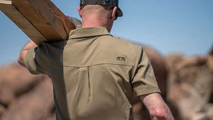 Male hunter carrying wood outside while wearing a KUIU Motive t-shirt.