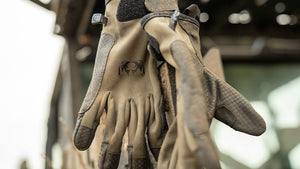 Closeup of a pair of rugged Ash Attack Gloves in Ash hanging from the side of a truck outside.