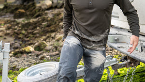 Male wearing Attack Pants in stone with dirt all over him as he adjusts a trailer to a truck.