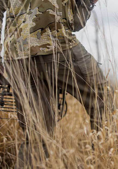 Back of Hunter Stalking Game With Bow Wearing Attack Pants in Ash Brown Color