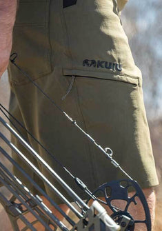 Side of Hunter Holding Bow Wearing Switchback Shorts in Khaki Color
