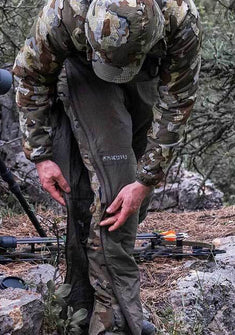 Front of Hunter Zipping Up Kenai Pants in Ash Brown Color Highlighting Full Length YKK Zippers