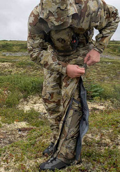 Front of Hunter Zipping Up Chugach TR Rain Pants in Valo Camouflage Highlighting Full Length YKK Aquaguard Zippers