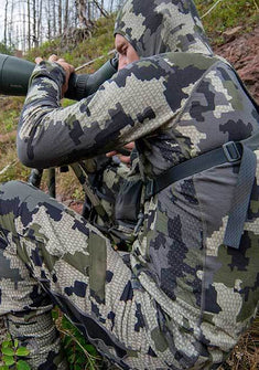 Side of Hunter Glassing Game in Spotting Scope Wearing Ulra Merino 145 Zip T Hoodie in Verde Camouflage