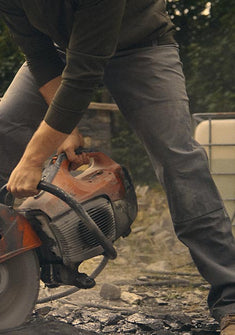 Man using a demo saw to cut through a slate rock, wearing Brawley Pant in Gunmetal
