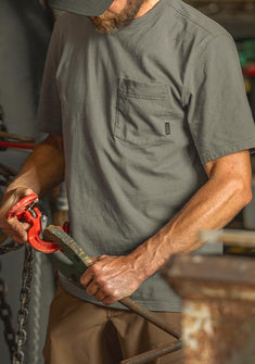 Man connecting chains in a workshop setting, wearing Workgrade Short Sleeve Pocket Crew in Castle Rock Grey