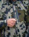 Detail of main zipper being pulled up by hunter on Chugach TR Rain Jacket in Verde Camouflage