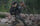 Kevin Wilkerson in Verde camouflage hunting gear and hat hikes through a rocky forest trail, carrying a large ICON 6 backpack with a Dall Sheep antlers and using two trekking poles.