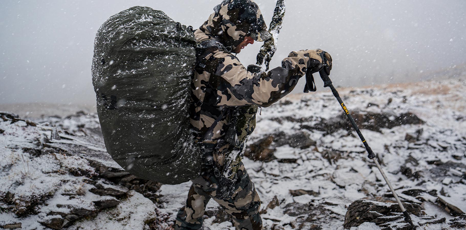A hunter backpacking across a snowy mountain.