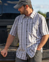 Hunter leaning behind the tailgate of his truck wearing Borrego SS Shirt in Grey Granite Plaid