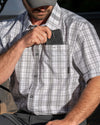 Hunter slipping a cellphone in his left chest pocket on the Borrego SS Shirt in Grey Granite Plaid