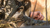 Hunter sitting in brush wearing StrongFleece Valo Camouflage knitted hard-faced shirt