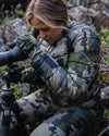 Hunter Watching Game Through Spotting Scope Wearing Women's Super Down LT Jacket and Pants in Verde Camouflage