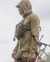 Hunter wearing Gila Pro Long Sleeve Hoodie in Khaki carrying a hunting bow looking into the distance
