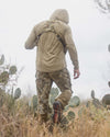 Back of hunter walking amongst cacti wearing the Gila PRO LS Hoodie in Khaki with hood on
