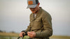 Hunter Tightening Field Points on Arrows Wearing Base Camp Insulated Snap Shirt in Ash Brown Color