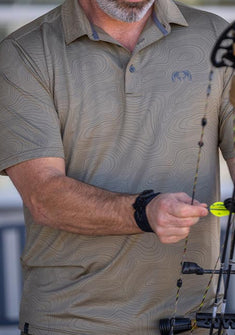 Close-up of Hunter wearing KUIU Performance Polo in Khaki Topo, adjusting an arrow on his bow