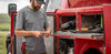 Man holding a wrench, standing beside his work truck, while wearing the KUIU Workgrade Pocket Crew T-Shirt