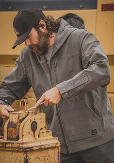 A man wearing Brawley Hooded Fleece Jacket in Gunmetal Grey operating a heavy-duty hardware tool.