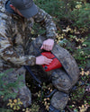 Man kneeling with PRO LT 4000 Bag in Valo Camouflage on the ground stuffing a zip dry bag into the front pouch