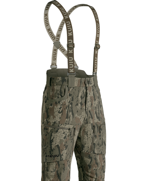 Veros Camouflage Proximity Insulated Pant with adjustable suspenders, featuring a digital camo pattern in shades of green, brown, and gray, with the KUIU brand name printed on the suspenders and leg.