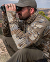 Hunter sitting down, glassing, wearing Gila Long Sleeve Crewneck Shirt in Valo Camouflage