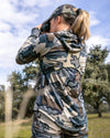 Back of female hunter, glassing, wearing Women's Gila LS Hoodie in Vias Camouflage showing length of garment