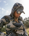 Female hunter adding Women's Gila LS Hoodie in Vias Camouflage as a layer